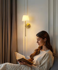 Legit Dope Gold Cordless Wall Sconces Set Of Two With Soft Beige Fabric and Warm LED lighting illuminating a woman reading.