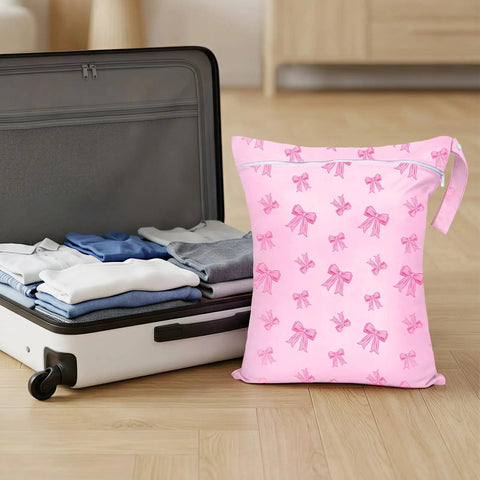 Large Waterproof Travel Laundry Bag Set For Wet Dry Gear, pink bow pattern next to packed suitcase, reusable drawstring pouch
