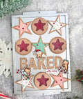 Holiday-themed scrapbook card design with cookies, snowflakes, and the word 'Baked' in a festive setting.