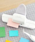 Adjustable Postage Stamp Border Punch For Scrapbooking And Card Making, stamp shaped paper punch in mauve finish on grid mat