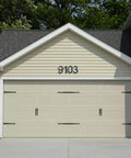 Garage with beige panel doors and black 9103 address sign, featuring 10 Inch Aluminum Floating House Number 2 in Black