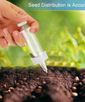 Hand using Mini Seed Dispenser And Hand Seeder Tool For Garden Planters No Fuss Sowing Precise Seed Spreader For Flowers Vegetables Fruit Trees And Grass Seed Easy Sowing No Thinning Perfect Starter For Small Gardens over soil