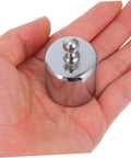 Person holding 200g weight for high precision calibration weights for digital scales and lab use, even weight distribution.