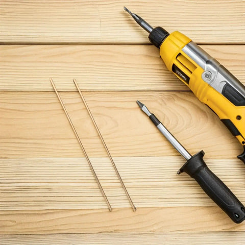 Two Brass Knife Pins For DIY Knife Handle Kits And Repairs, shown alongside a yellow electric drill and screwdriver on wooden surface.