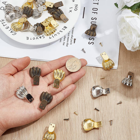 Hand holding decorative Dope Antique Zinc Alloy Feet Set 30 Pieces In 3 Colors for furniture, next to coin for size comparison.