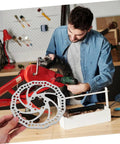 Fire Up Your Rig With This Mountain Bike Front And Rear Mechanical Disc Brake Kit Featuring Forged Aluminum Calipers Premounted Pads And Direct Pull Cables For Solid Stops On Wild Trails All Season Long, showing silver disc brake in workshop.