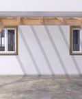 Wooden carport attached to a building with two windows, featuring wooden beams and a slanted roof design.