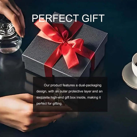 Black gift box with red ribbon, hand holding water glass, perfect gift text, cup and saucer on dark tabletop.