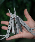 Hand holding 13 In 1 Stainless Steel EDC Multitool With Nylon Sheath for Camping, Hiking, and Fishing, showing tools extended.