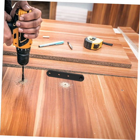 Concealed hinge plate (stainless steel) with three mounting holes on wooden workbench; drill and tools nearby.