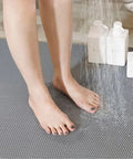 Feet on Commercial Drainage Mat Non Slip Floor Mat 3x10 Ft 0.22 Inch Thick For Wet Areas; grey cushioned mesh with water spray.