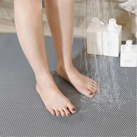 Feet on Commercial Drainage Mat Non Slip Floor Mat 3x10 Ft 0.22 Inch Thick For Wet Areas; grey cushioned mesh with water spray.