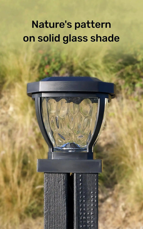Solar Post Cap Lights With Decorative Glass LED Outdoor Post Lighting For Three And A Half Inch Posts Black Two Pack Weatherproof Pathway Vibe Long Lasting Warm LED Lighting For Nighttime Safety And Curb Appeal with glass detail against a garden background.