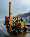 Workhorse Guardrail Post Driving Machine For Highway And Roadside Construction Projects in rainy weather on a road.