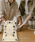 Two people using a Roman Column Ball Mold For Concrete DIY Projects on a table, crafting a decorative sculpture.
