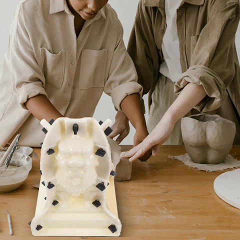 Two people using a Roman Column Ball Mold For Concrete DIY Projects on a table, crafting a decorative sculpture.