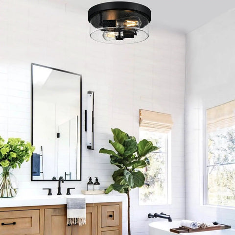 Two Light Black Flush Mount Ceiling Light Fixture With Seeded Glass Shade installed in a modern bathroom setting.