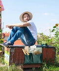 Man sitting outdoors with foldable portable garden tool pouch and kneeling stool bag attached to wooden bench, tools visible