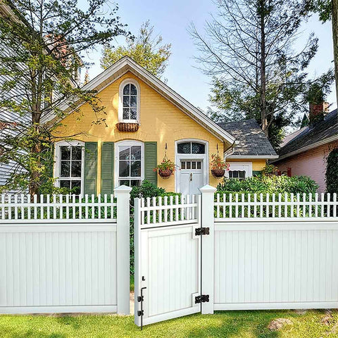 White vinyl gate with 36 Inch Cane Bolt Gate Drop Pin And Drop Rod in front of a yellow house with green shutters and garden