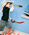Child playing pirate with Premium Brass Spyglass Telescope With Pocket Compass Set For Outdoor Adventures, wearing paper hat.