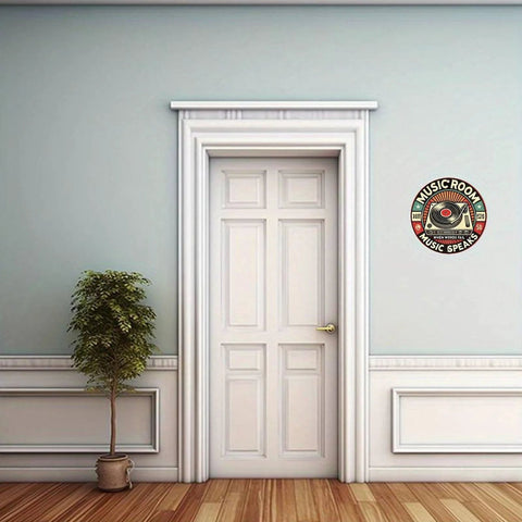 Round 8in aluminum music room wall sign with turntable design mounted on a light blue wall beside a white paneled door