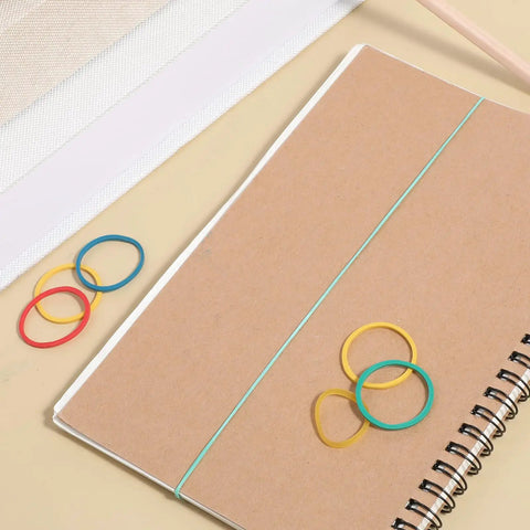 60 Pcs Rubber Pulley Belt Set For RC Cars Airplanes Robots Trucks And DIY Models Durable Transmission Belts In Multiple Sizes 23mm To 60mm Includes Colored Rubber Bands Must Have Replacement Parts And Toy Accessories placed on a notebook with colorful rubber bands.