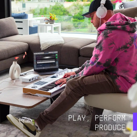 Person using MiniFuse 2 USB Audio And MIDI Interface for recording with laptop and keyboard in a home studio setup.