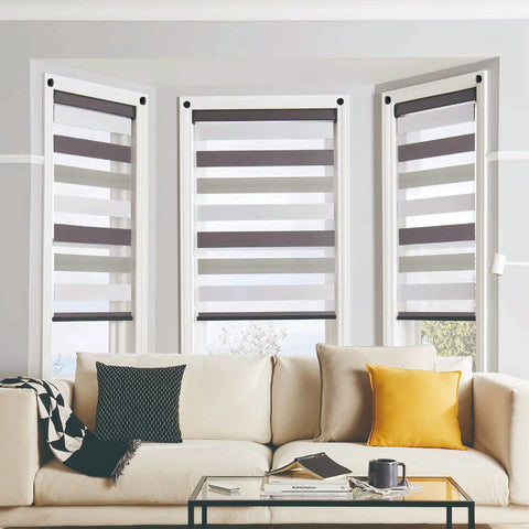 Modern living room with beige sofa, yellow cushion, and striped window shades. Large windows provide natural light.