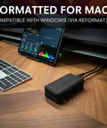 Beast 2TB External NVMe SSD With Thunderbolt 3 Ultra Fast 2800 MBs Read 2600 MBs Write For 4K 8K Editing VR And Big Media Backups Fanless Rugged Aluminum Enclosure Meets MIL STD 810F on desk with Mac and tablet