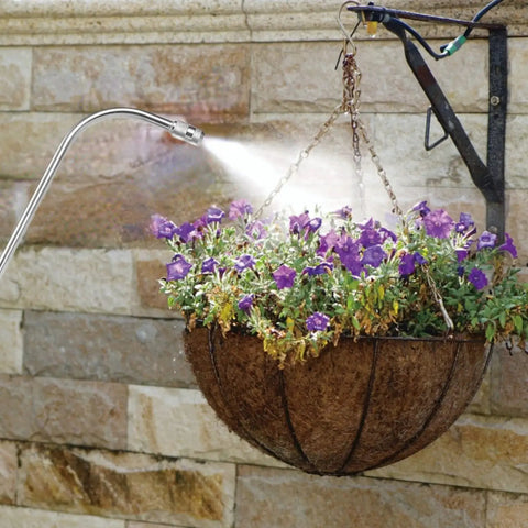 25 Inch Spray Wand With Adjustable Nozzle For Hanging Baskets And Plants watering purple flowers in a hanging basket outdoors.