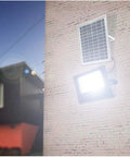 JUDYSSY Solar Flood Lights 60W Solar Outdoor Patio Lighting mounted on wall with solar panel and bright LED light.