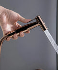 Top Shelf Wall Mounted Rain Shower Combo Set With Smooth Handheld Sprayer And Bathtub Faucet Featuring Sleek Rose Gold And Matte Black Finish, hand holding the sprayer.