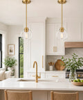 Two Pack Brass Pendant Lights With Clear Glass Globe Shades Farmhouse Gold Hanging Lamps over a kitchen island.