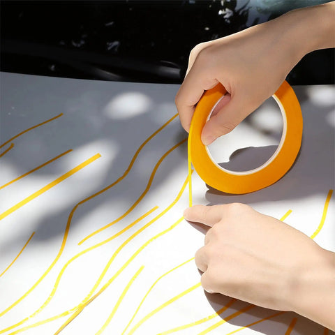 Hands applying Four Pack Painters Tape Set With 1/16, 1/8, 1/4 And 1/2 Inch Widths, 52 Yards Each on a surface for automotive DIY masking.