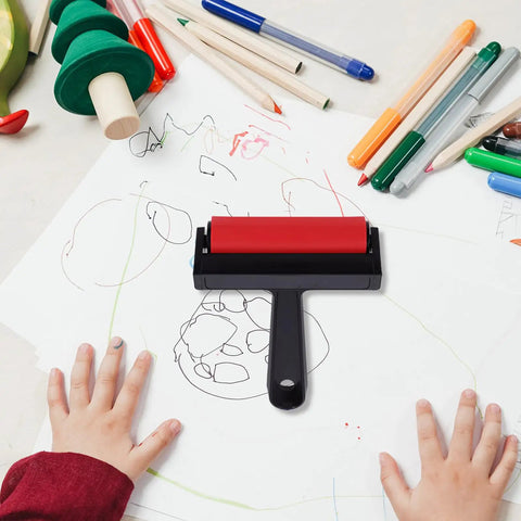 Solid Grip Rubber Paint Roller For Printmaking And Classroom Art Projects with red frame on a cluttered art table.