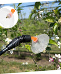 Two Pack Transparent Windproof Spray Nozzle Covers for garden hose in use, shielding flowers from wind during precise watering.
