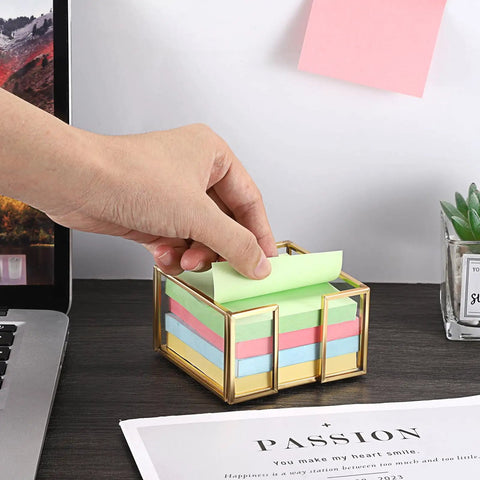 Hand reaching for a note in Gold Trimmed Glass Sticky Note Holder With Non Slip Pads For 3x3 Inch Notes Elegant Post It Dispenser on desk