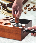 Solid Wooden Espresso Tamping Station With Fully Integrated Knock Box And Precision 58Mm Tamper Stand For Sapele Wood in use with tamping tool.