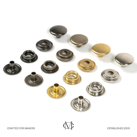 Assorted metal snap fasteners displayed in rows, showcasing different finishes and designs for crafts.