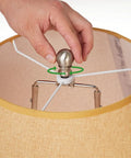 Hand securing a heavy brushed nickel ball lamp finial cap for lampshade top and lamp harp connection on table or floor lamp