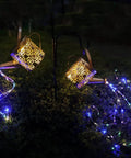 2 Pack Solar Watering Cans With Cascading Lights illuminating a garden, metal retro waterproof hanging lanterns, daisy pattern design.