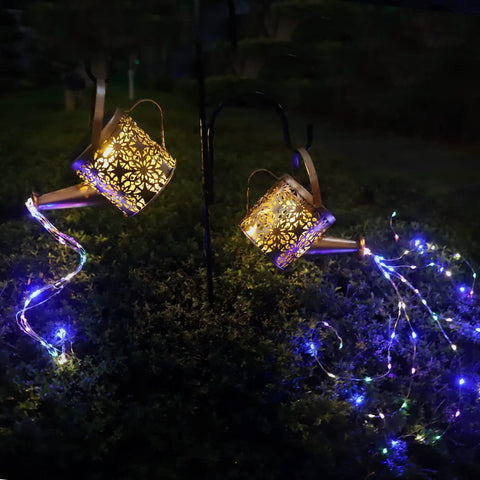 2 Pack Solar Watering Cans With Cascading Lights illuminating a garden, metal retro waterproof hanging lanterns, daisy pattern design.