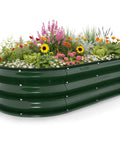 Sturdy Galvanized Steel Raised Garden Bed With 12 Inch Depth Oval Open Bottom Design Yard Ready No Fuss For Outdoor Veggies And Herbs 4X2 Foot Frame Easy Ground Level Gardening Forest Green filled with blooming flowers and herbs.