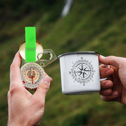 Holding a Thumb Type Orienteering Navigation Tool For Backpacking And Hiking Accurate Directional Map Compass near a compass mug.
