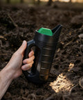 Hand holding a Three Opening Adjustable Handheld Seed Spreader With 90 Ounce Capacity on soil in a garden setting.
