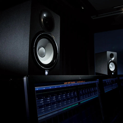 HS7 7-Inch Powered Studio Monitor Pair With Bi-Amp System placed in a dimly lit home studio environment.