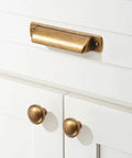10 Pack Antique Brass Cup Pulls For Kitchen Cabinets And Furniture, 3 Inch Hole Center Drawer Pulls shown on white cabinet doors