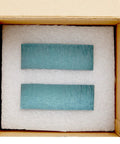 Blue rectangular objects inside cardboard box with padding for protection.