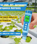 Hand holding 4 In 1 Digital pH Meter EC TDS And Temperature Tester for Hydroponics and Water Quality above plant tray.