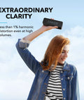 Woman holding Upgraded Bluetooth Speaker With IPX5 Waterproof, Rich Stereo Sound, Deep Bass, And 24 Hour Playtime, Your Go To Portable Wireless Speaker For iPhone, Android And More, Black outdoors against blue sky